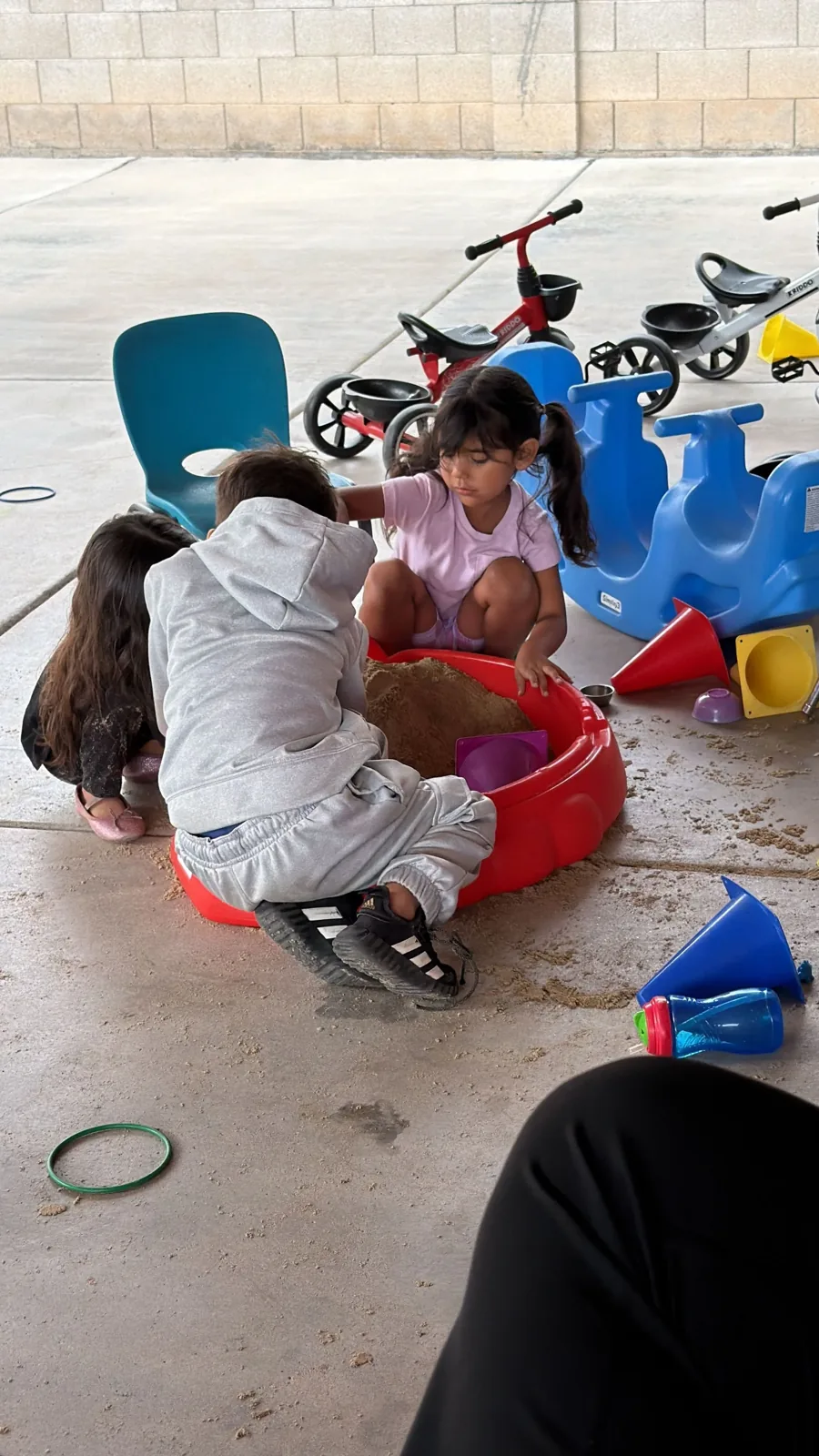 Two toddlers playing in the sandbox in the yard